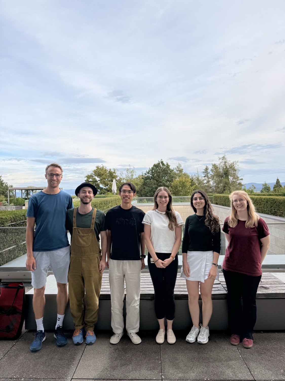 Six members of the TAPPAS editorial team standing in a row on a terrace, with trees and hills behind them